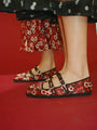 Shin down crop of two women wearing red floral-patterned shoes against a red sleamless