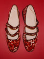 Pair of red floral-patterned shoes on a red background