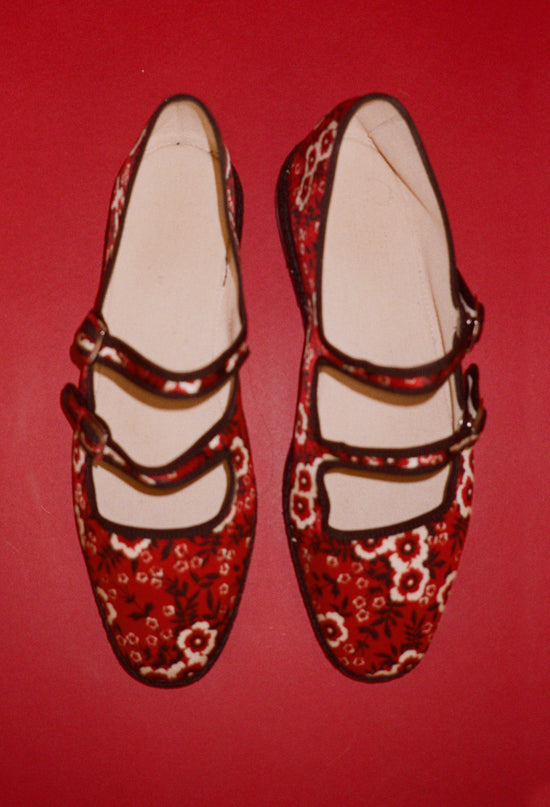 Pair of red floral-patterned shoes on a red background