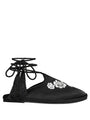 Black slip-on shoes with white floral embroidered in the top and twist-cord ties with tassels to wrap around the ankle on a white background