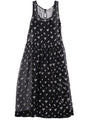 Long black sleeveless sheer dress with small white floral embroidery and drop waist against a white background