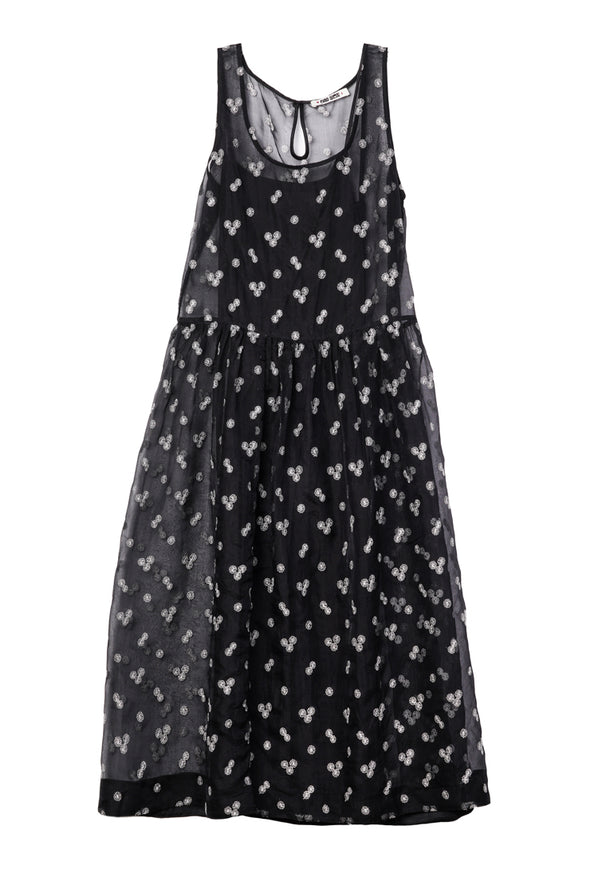 Long black sleeveless sheer dress with small white floral embroidery and drop waist against a white background