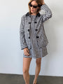 Woman wearing a black and white checkered gingham jacket and matching mini dress against a plain background