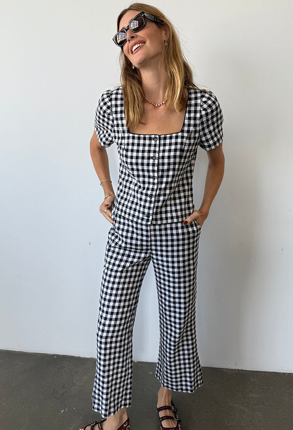 Woman wearing a black and white checkered gingham short sleeve top with matching pants against a plain background