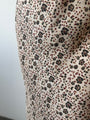 Cropped detail shot of a silky skirt with floral cherry blossom pattern against a plain background