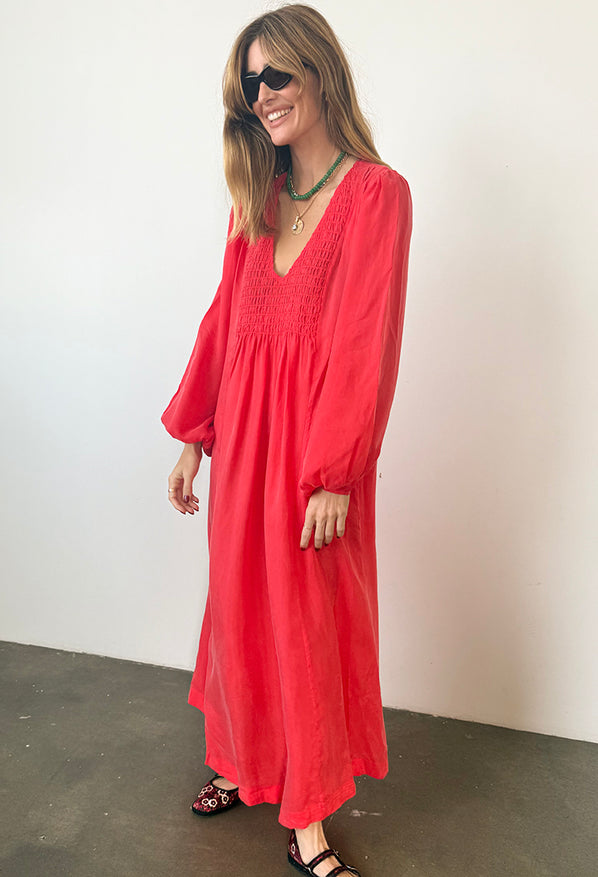 Woman wearing a red caftan dress against a plain background
