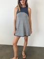 Woman in a striped white and navy tank style knit dress against a plain background